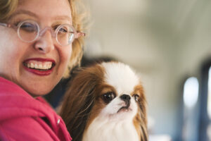 A woman in a pink sweatshirt holds a Japanese Chin on an historic train.